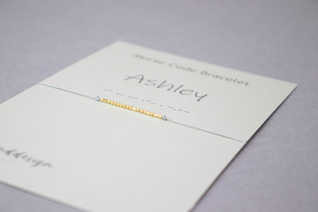 Personalized Morse code bracelet on its card, the name Ashley in silver beads