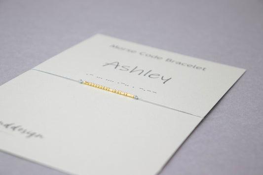 Personalized Morse code bracelet on its card, the name Ashley in silver beads