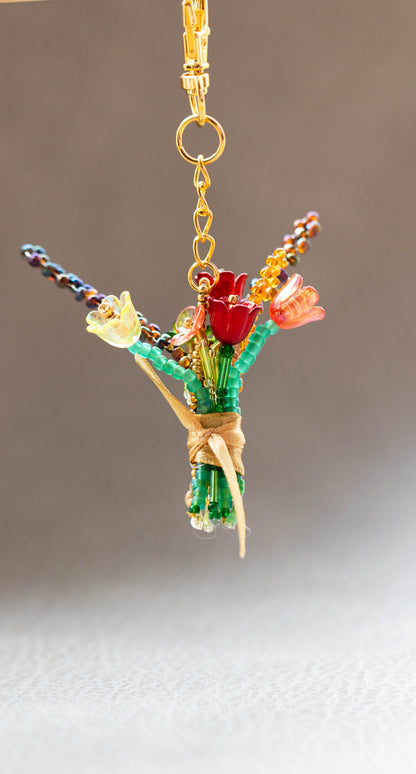 Colorful flower-shaped keychain with gold chain on a neutral background