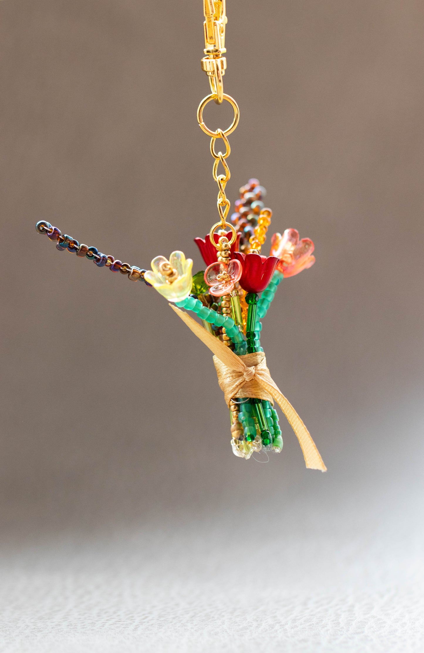 Keychain with floral design and gold accents on a neutral background
