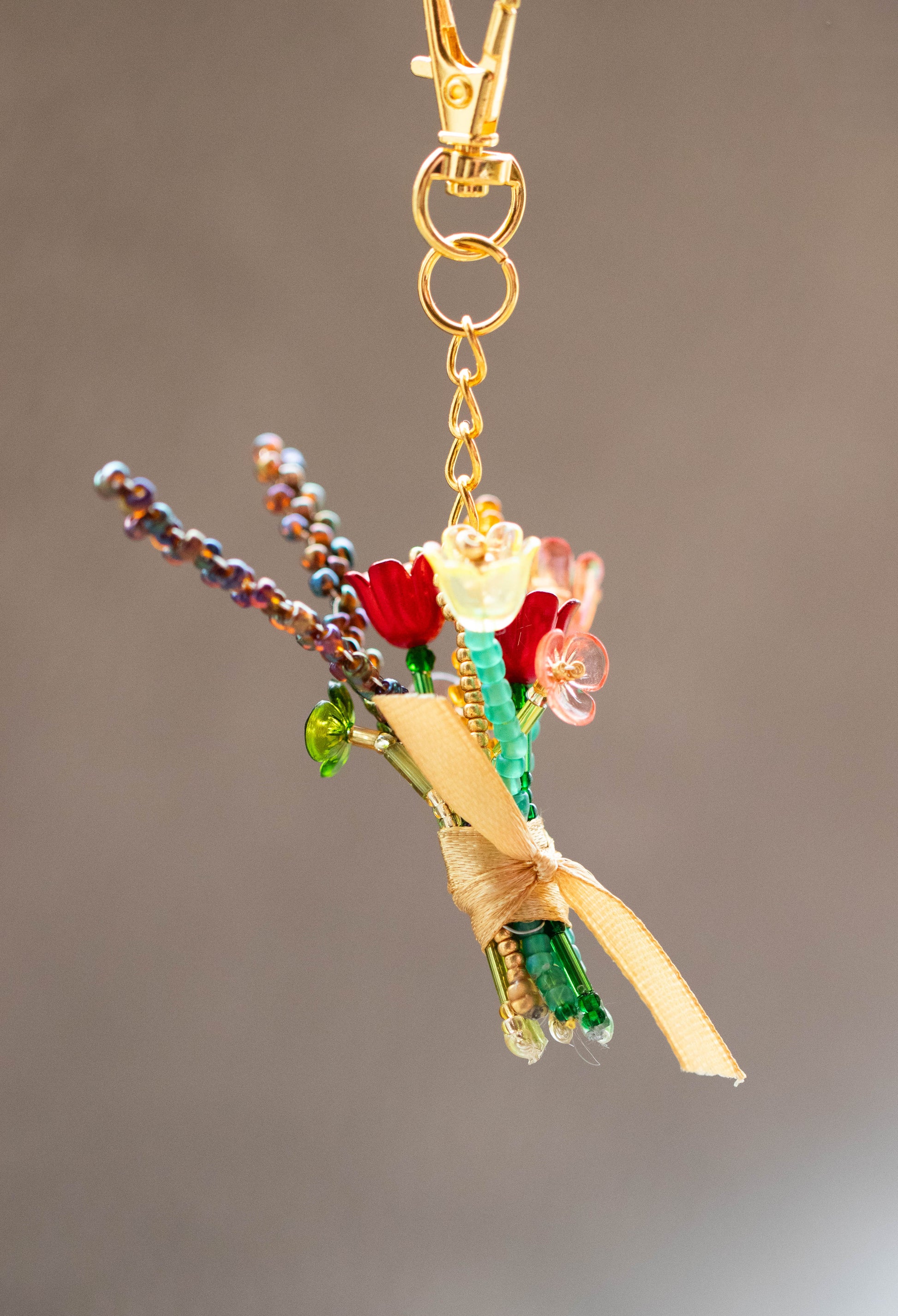 Decorative keychain with flowers and beads on a plain background