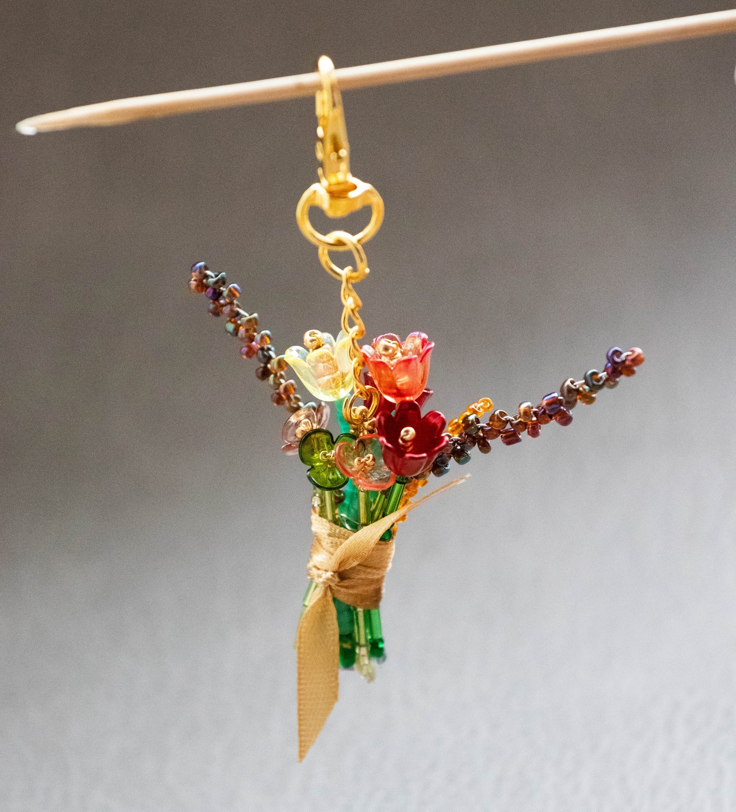 Bouquet-shaped keychain with colorful beads on a gray background