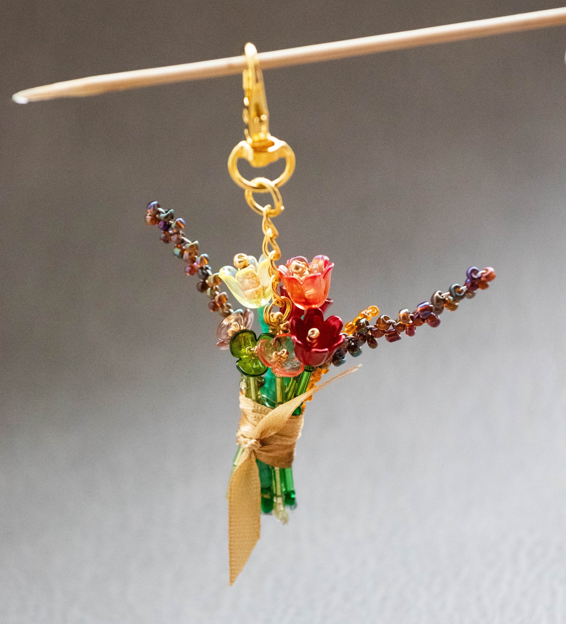 Bouquet-shaped keychain with colorful beads on a gray background