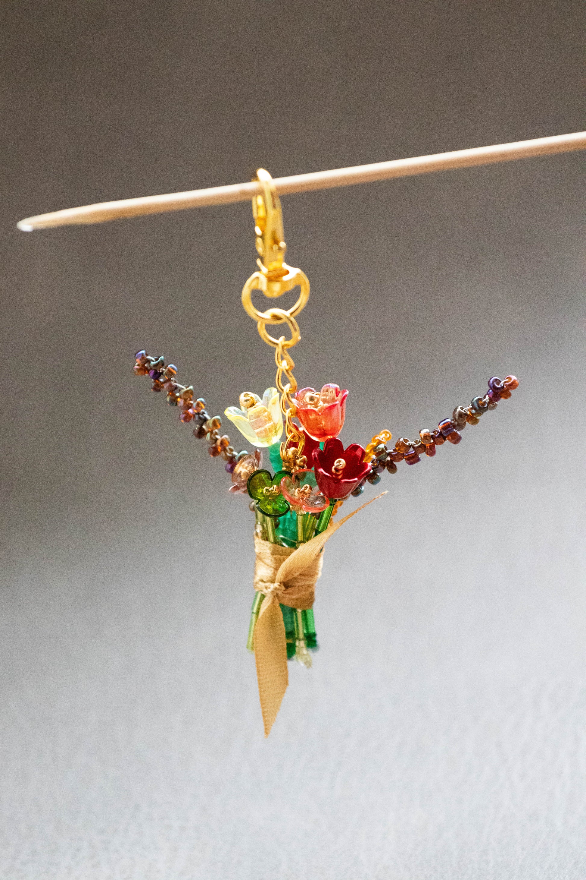 Colorful beaded bouquet charm on a stick against a neutral background