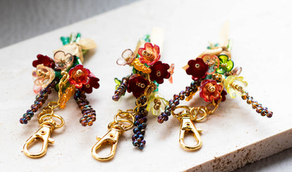Colorful beaded floral keychains on a light surface