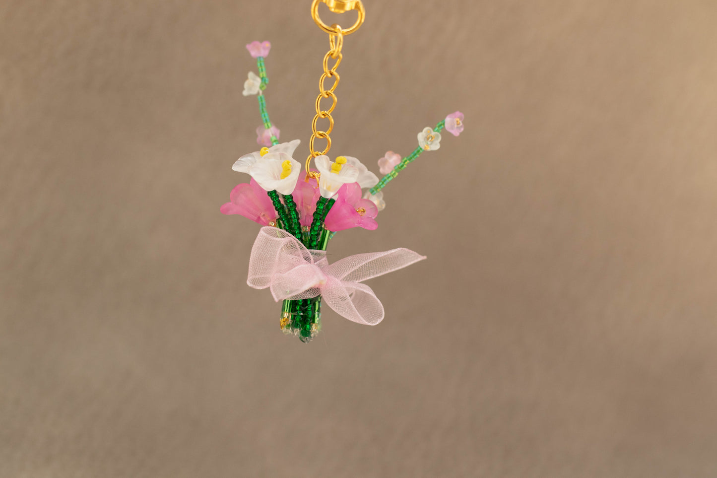 Floral keychain with pink ribbon on a beige background