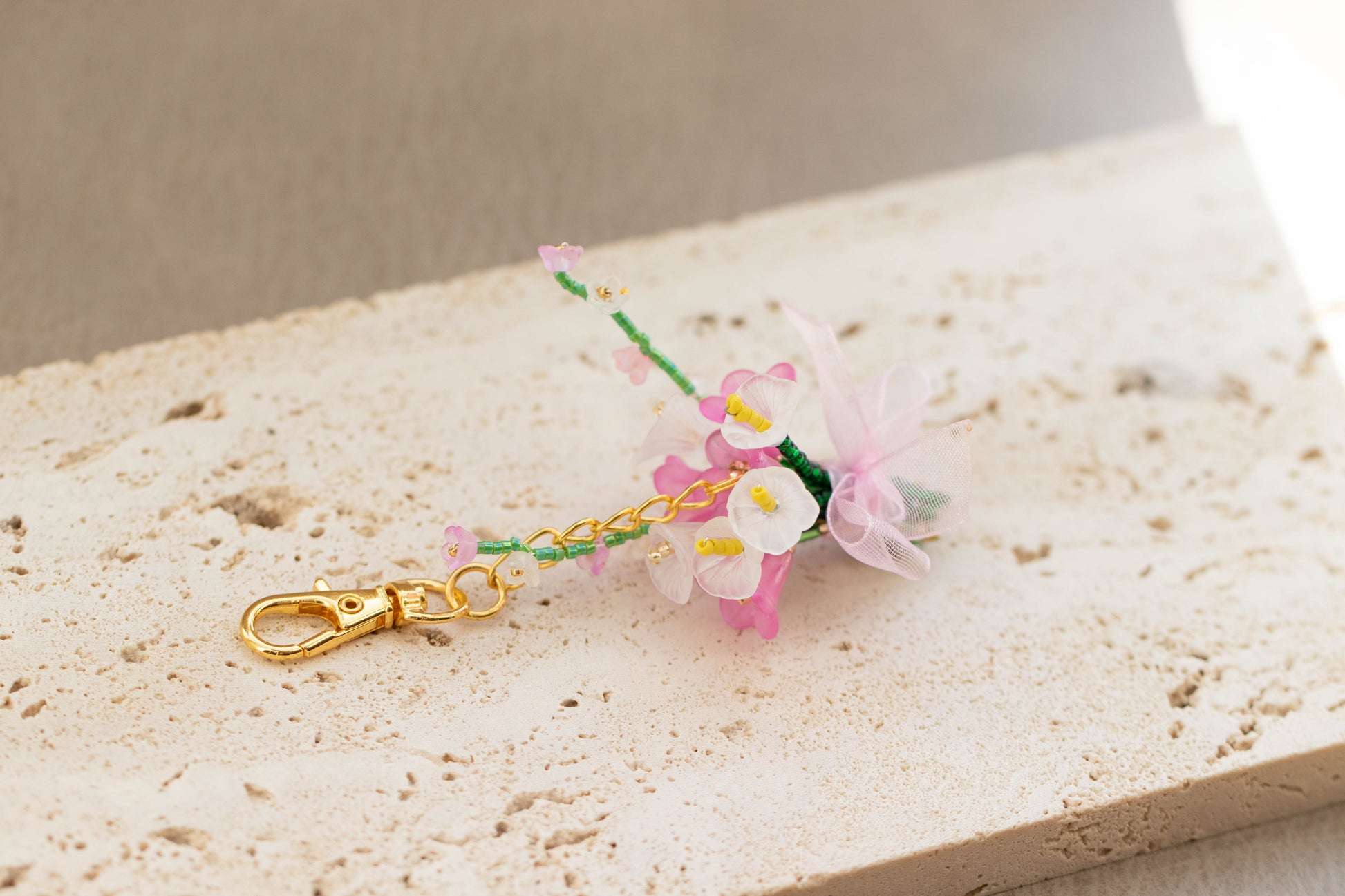 Floral keychain with gold clasp on a textured surface