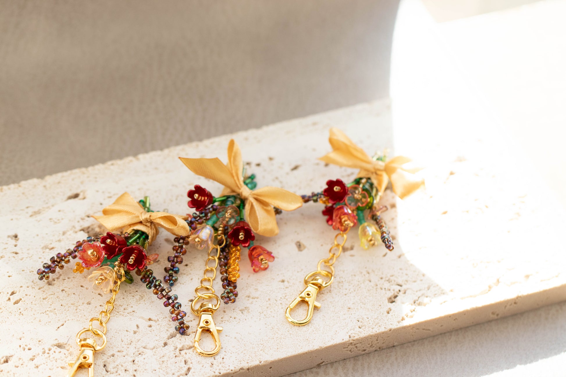 Decorative keychains with floral and bow designs on a stone surface