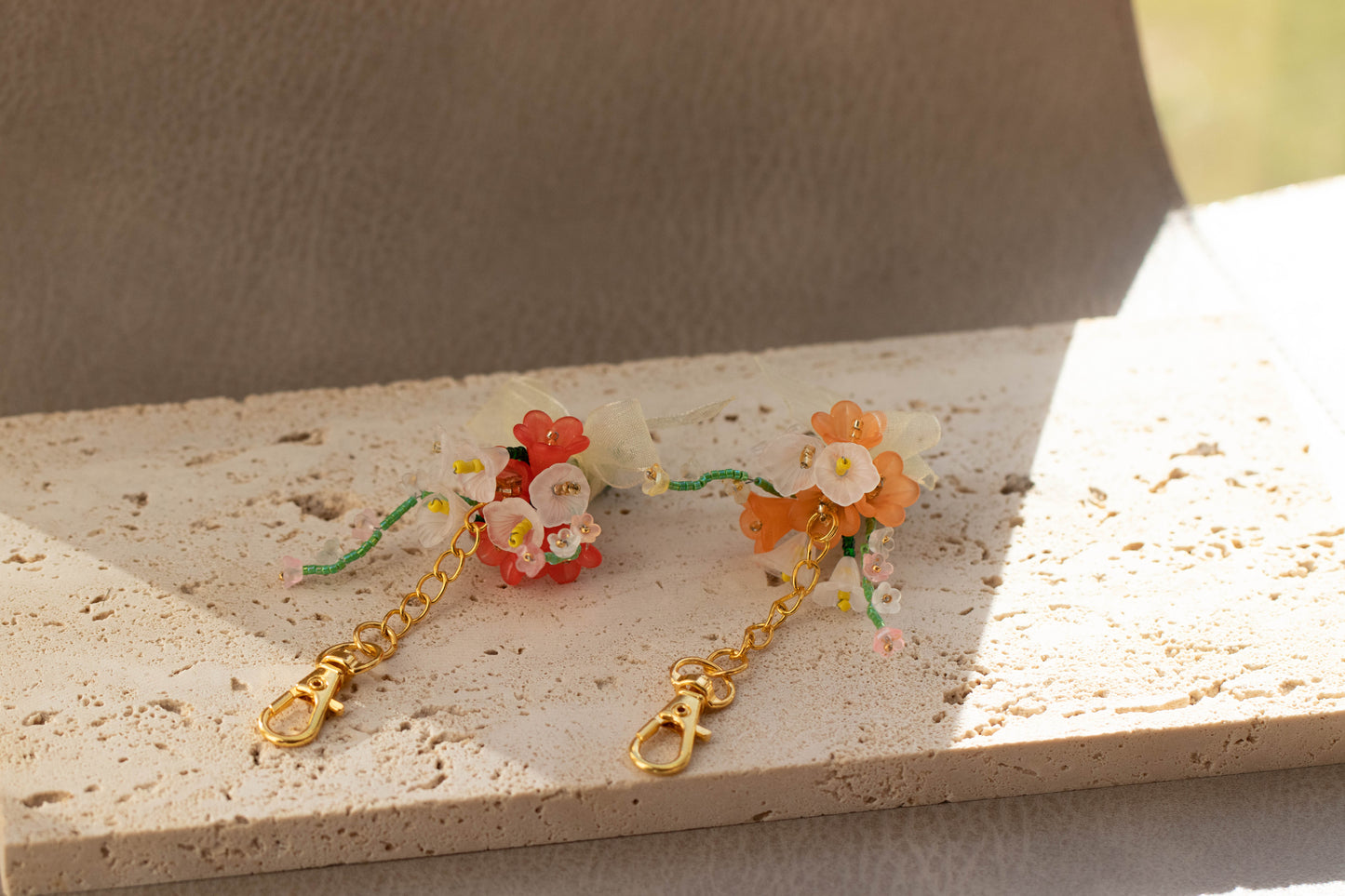 Floral earrings with gold chains on a textured surface