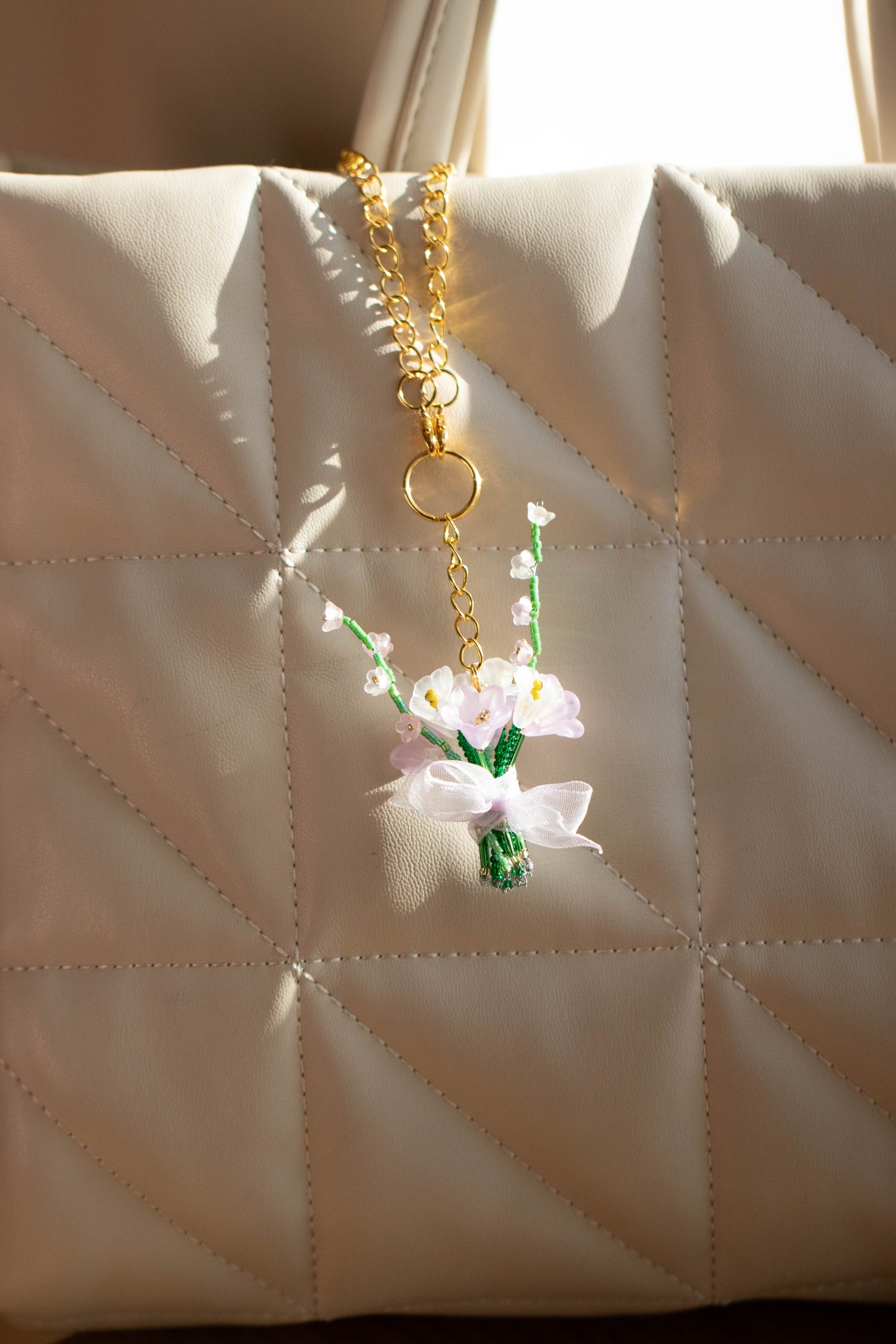 Floral keychain attached to a beige quilted handbag