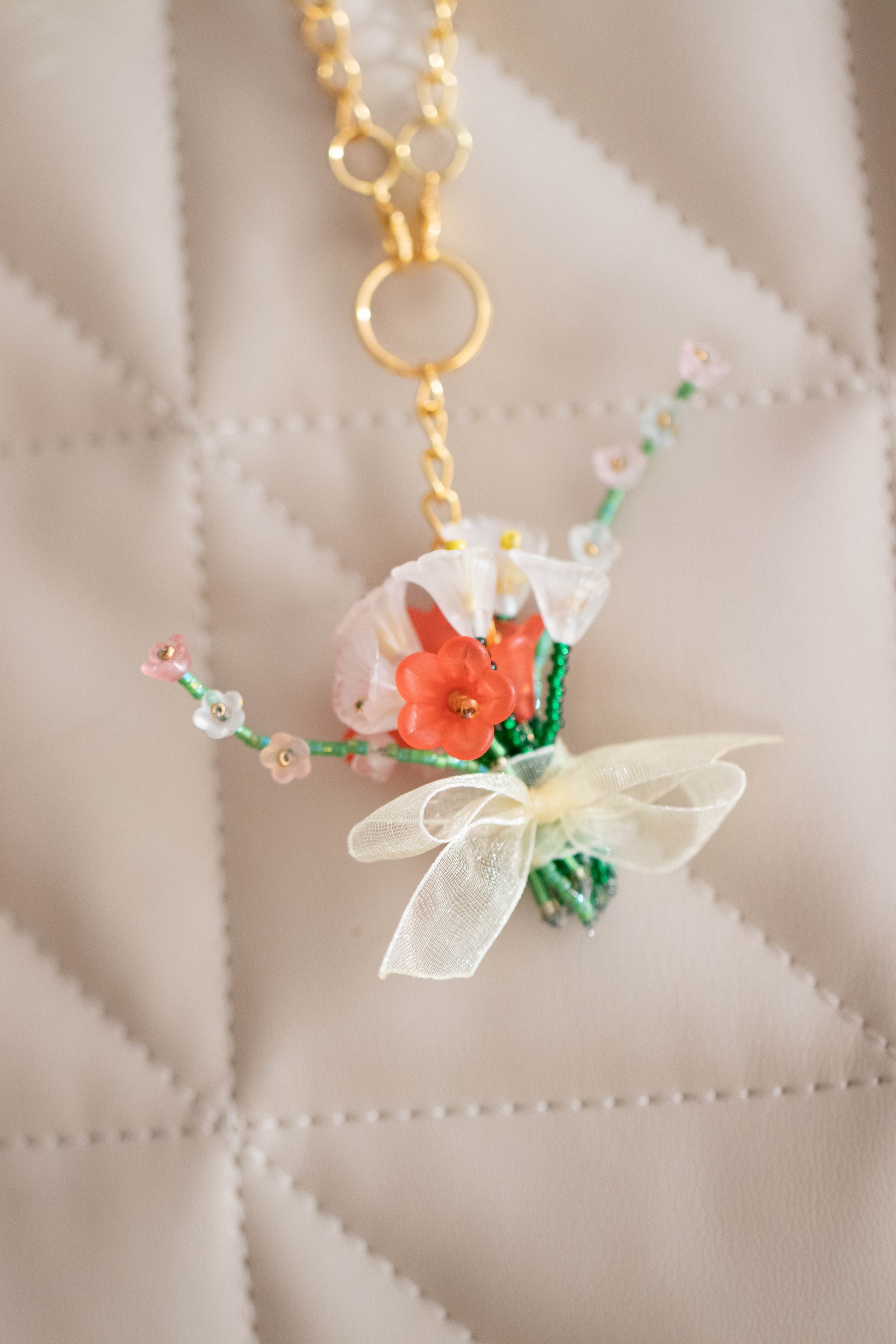Small decorative keychain with flowers and a bow on a beige quilted surface